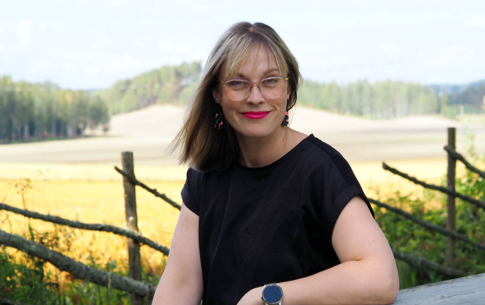 Rosie Dahlström lutar sig mot bord i lantlig miljö.