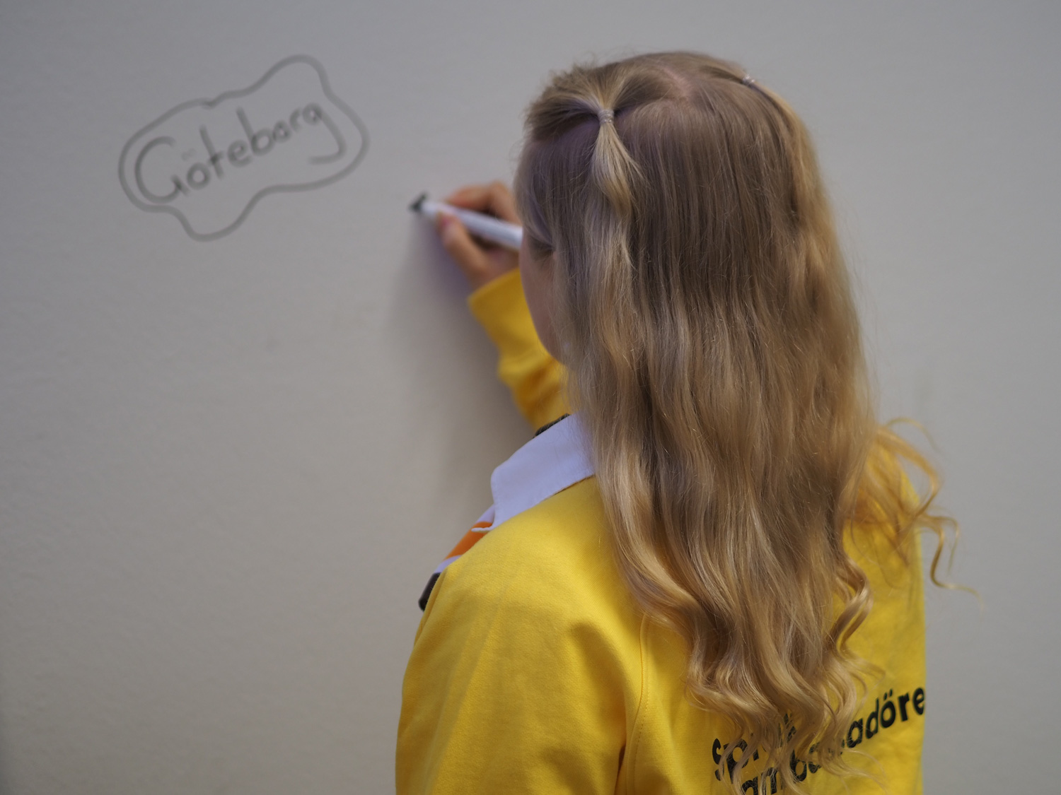 Kreetta Kiviniemi fotad bakifrån då hon skriver på väggen Göteborg.